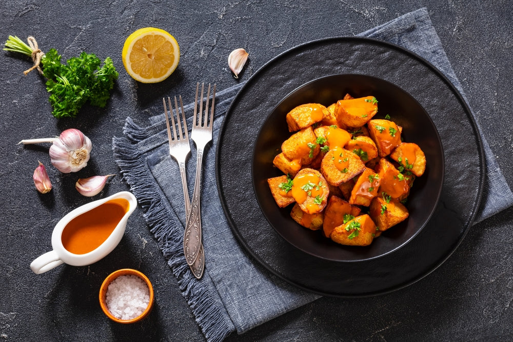 Patatas,Bravas,,Deep,Fried,Potatoes,With,Spicy,Sauce,In,Black